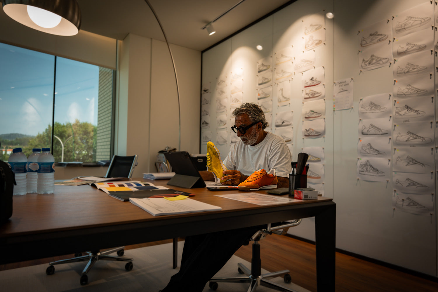 Le créateur de Semerdjian examinant des prototypes de chaussures orange et jaune dans son studio de design (Bureau)